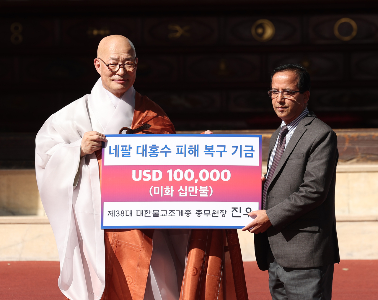 The Ven. Jinwoo (left), head of the 38th administration of the Jogye Order of Korean Buddhism, presents $100,000 in flood recovery aid for Nepal to Nirmal Prasad Bhattarai, charge d’affaires of the Nepalese Embassy in Korea, during his inauguration ceremony at Jogyesa in central Seoul on Thursday. (Lee Sang-sub/The Korea Herald)