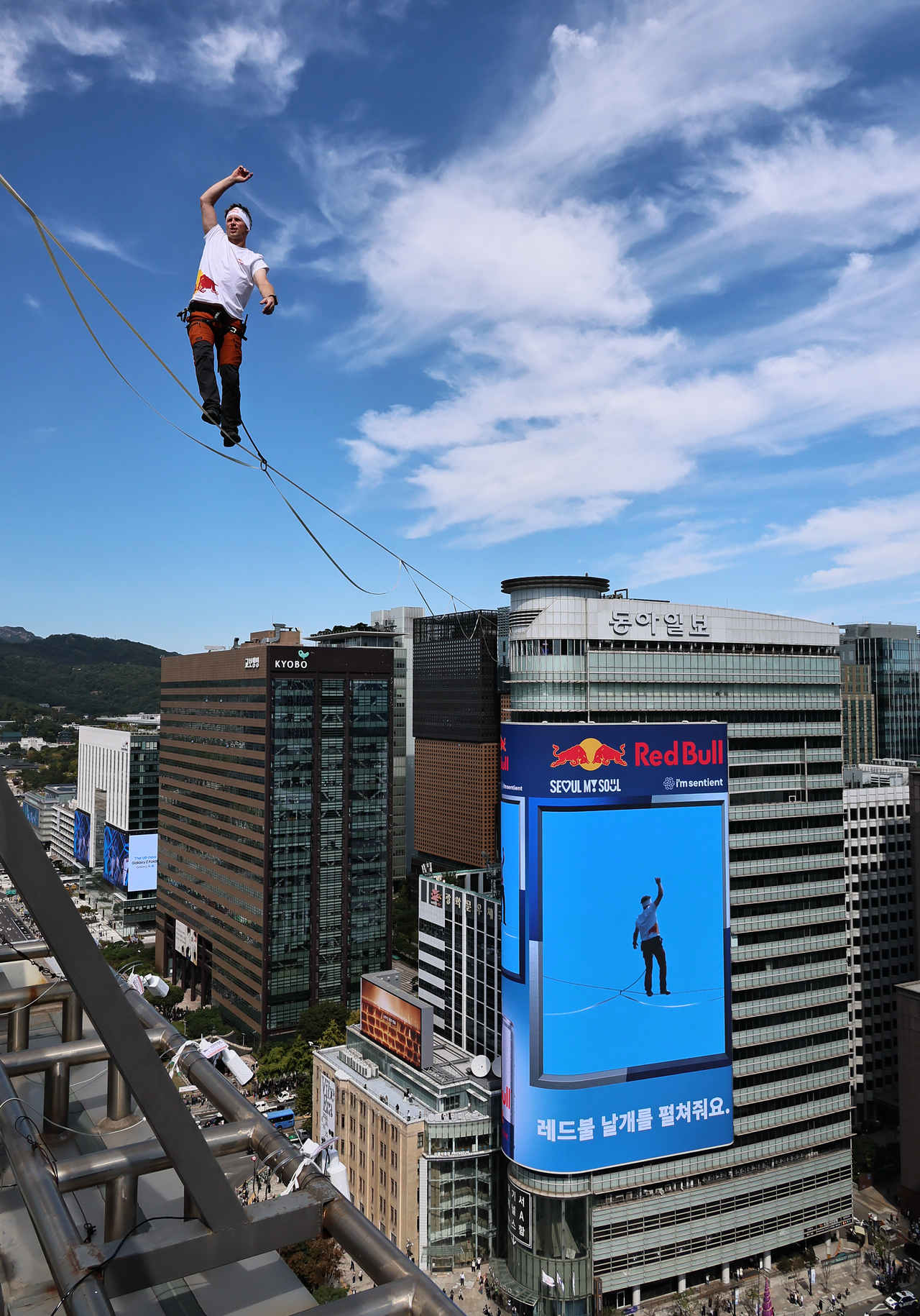 Slackline athlete Jaan Roose performs tricks 120 meters above the ground at Gwanghwamun Square in central Seoul on Thursday. (Yonhap)