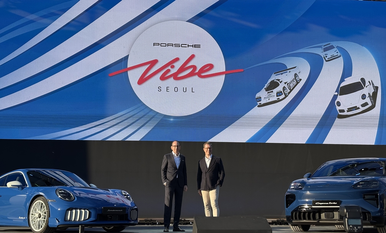 Alexander Fabig (left), president of product and individualization at Porsche AG, and Mathias Busse, CEO of Porsche Korea, pose for a photo with the Porsche 911 Turbo S Sonderwunsch (left) and the Cayenne Coupe Electric during a preview of Porsche Vibe Seoul at Oil Tank Culture Park in Mapo-gu, western Seoul on Friday. (Ahn Sung-mi/The Korea Herald)