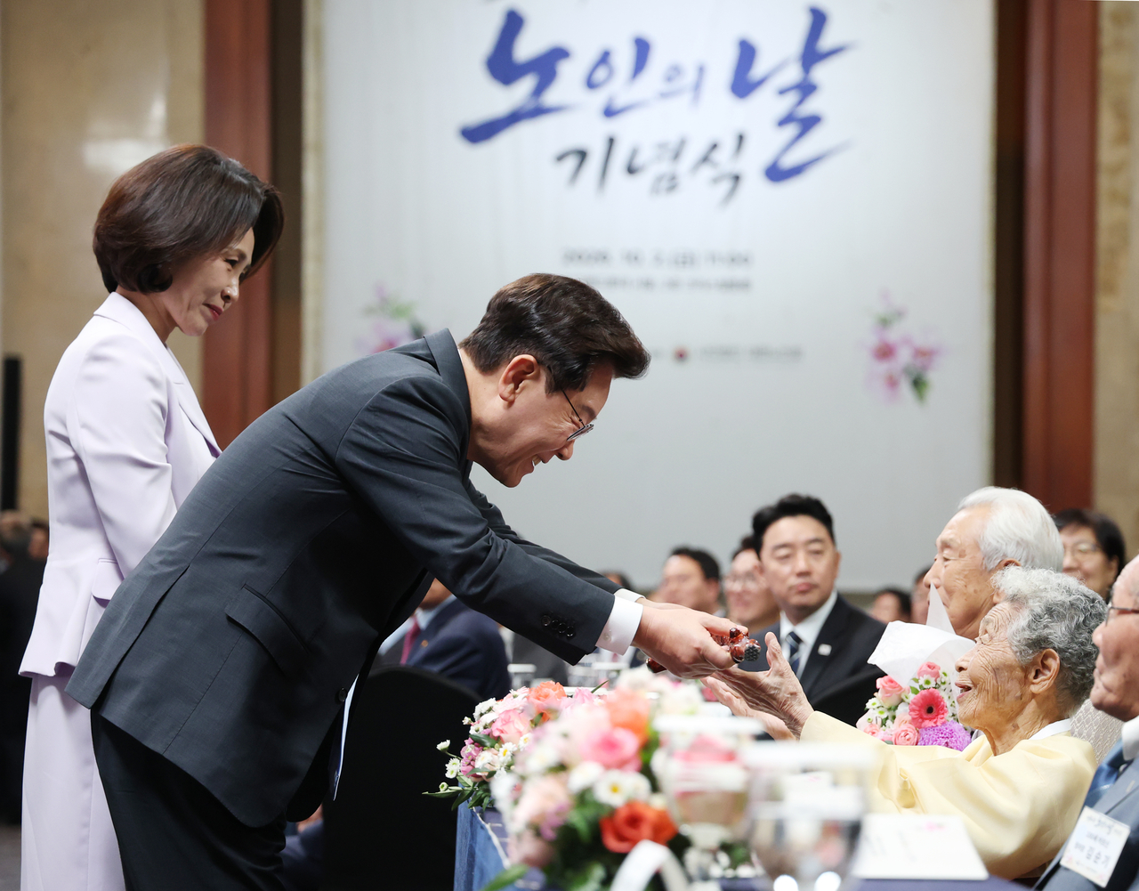 이재명 대통령이 2일 서울 한 호텔에서 열린 제30회 노인의 날 기념식에서 100세 어르신들에게 명아주로 만든 지팡이인 청려장을 전달하고 있다. [연합]