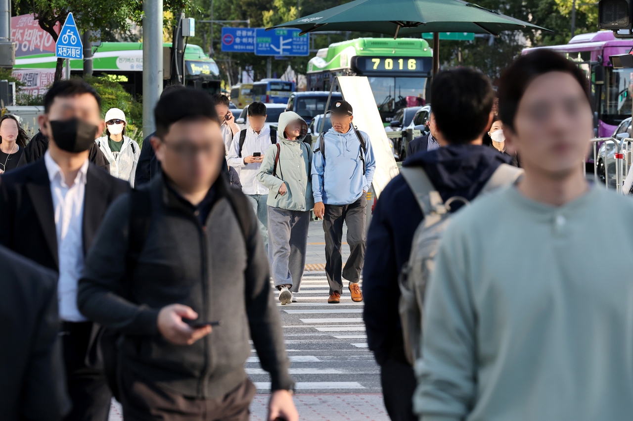 Commuters make their way to work along Gwanghwamun Street in Jongno-gu, Seoul, on Thursday morning as cooler weather sets in. [Yonhap]