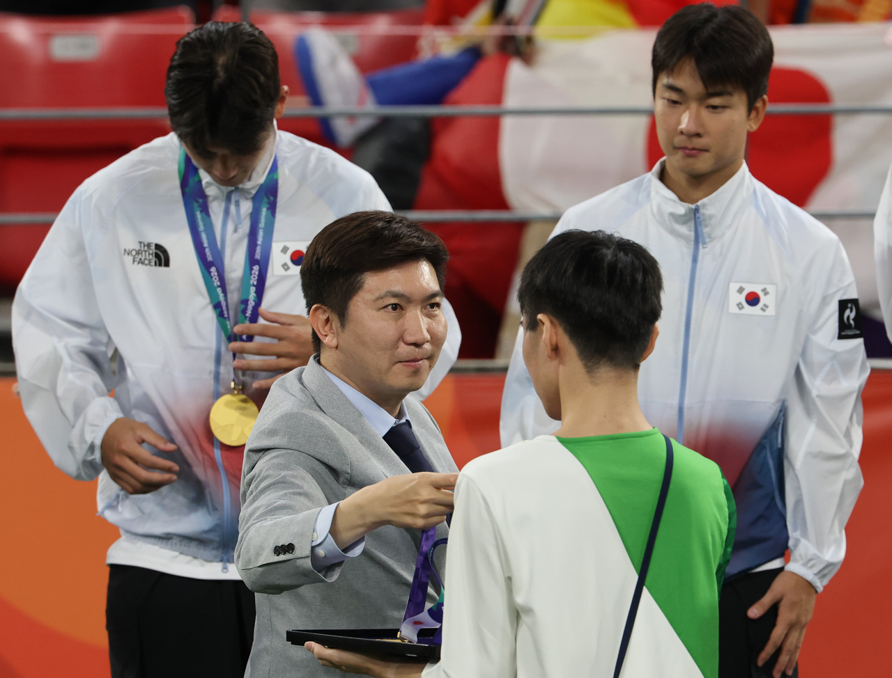 Korean Sport & Olympic Committee President Yoo Seung-min presents gold medals to South Korean players at the men's football awards ceremony at Toyota Stadium in Aichi Prefecture, Japan, on Saturday. [Yonhap]