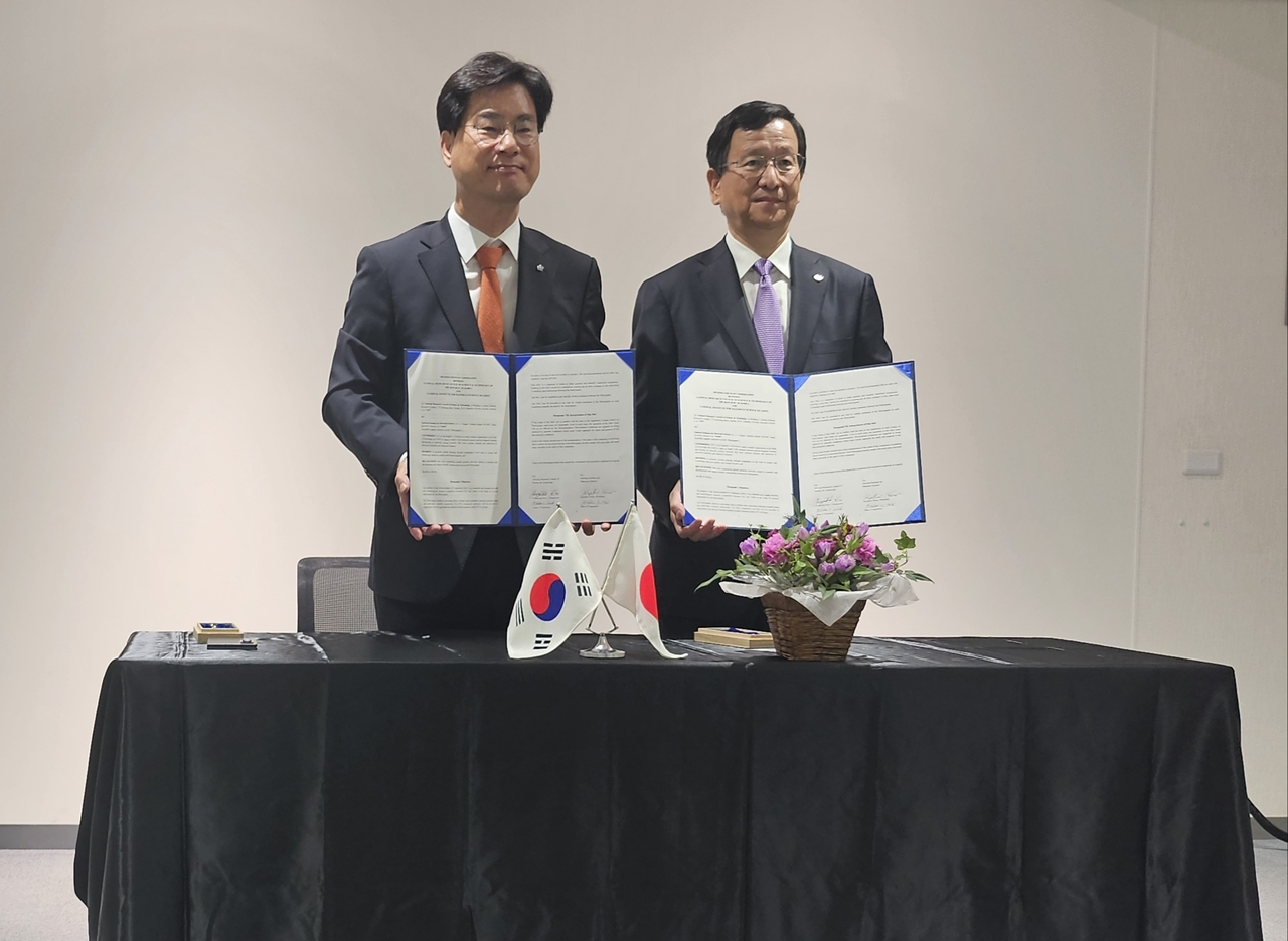 김영식(왼쪽) NST 이사장과 호노 가즈히로 NIMS 이사장이 업무협약서를 들어 보이고 있다.[NST 제공]
