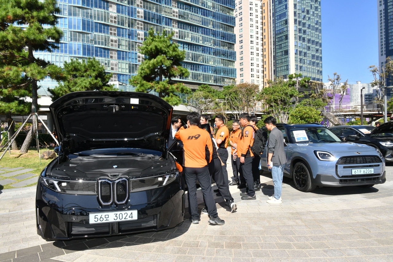 Firefighters from across South Korea examine a BMW iX3 and a MINI Countryman electric vehicle at the Electric Vehicle Safe Rescue Seminar for Firefighters held in Haeundae, Busan, learning about high-voltage battery layouts and safety precautions for cutting vehicle bodies. [BMW Group Korea]