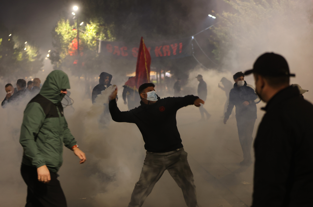 A protester throws back tear gas canisters at police units in Pristina, Kosovo, Monday. (AP-Yonhap)