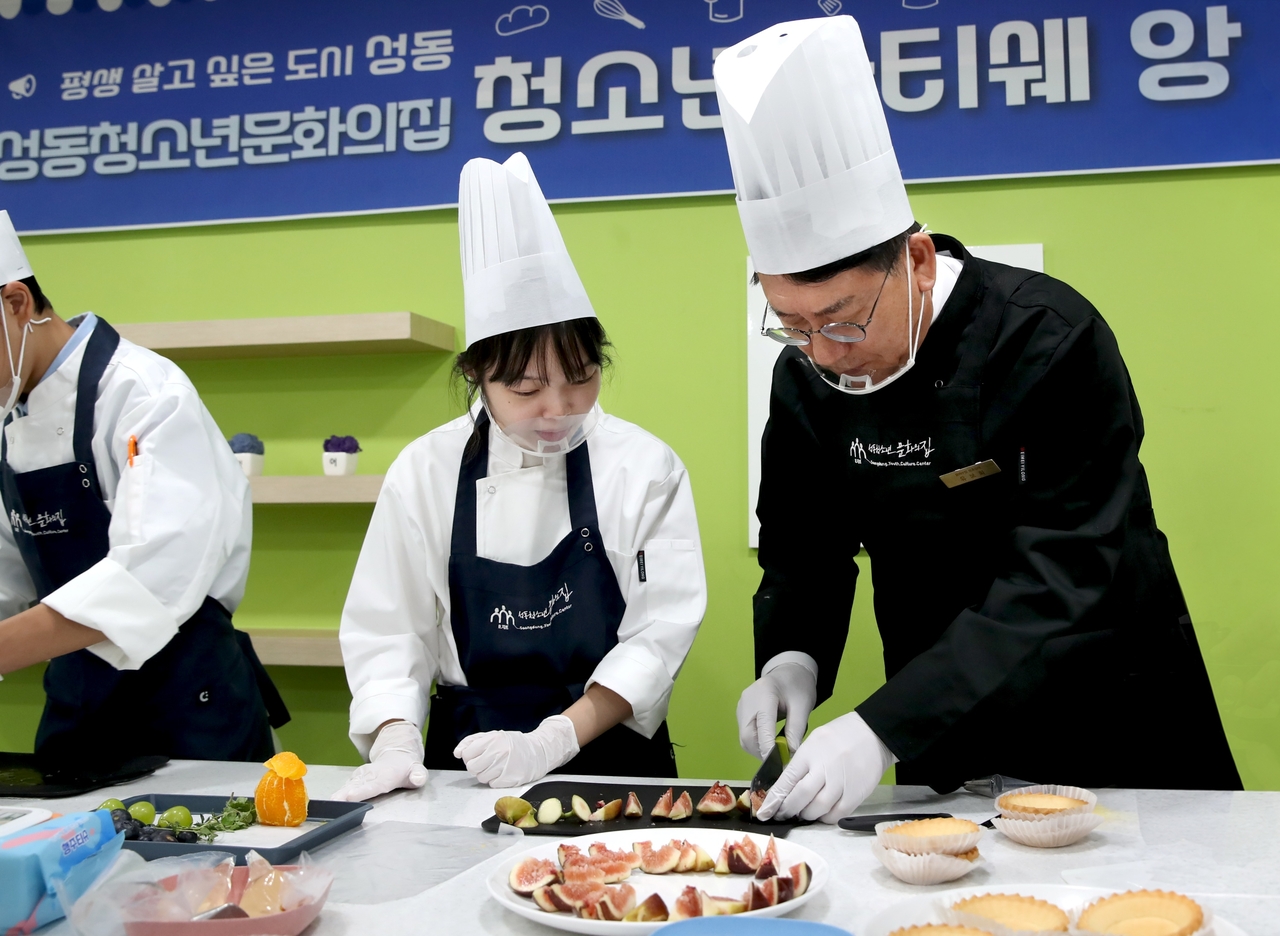 District Mayor Yoo Bo-hwa assists as a cooking class instructor