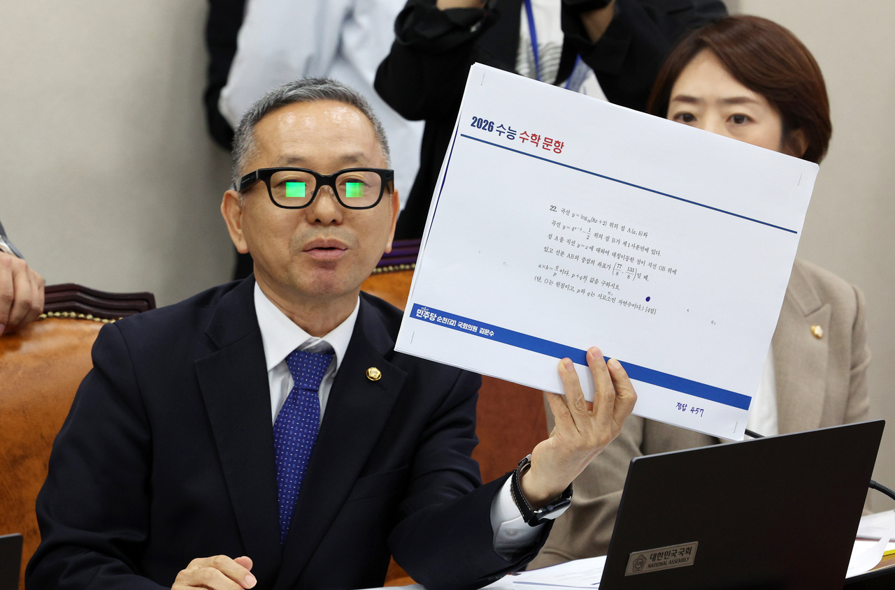 Democratic Party of Korea Rep. Kim Moon-soo holds up a question from the English section of the College Scholastic Ability Test while wearing AI-powered glasses during a parliamentary audit held at the National Assembly on Wednesday. (Newsis)