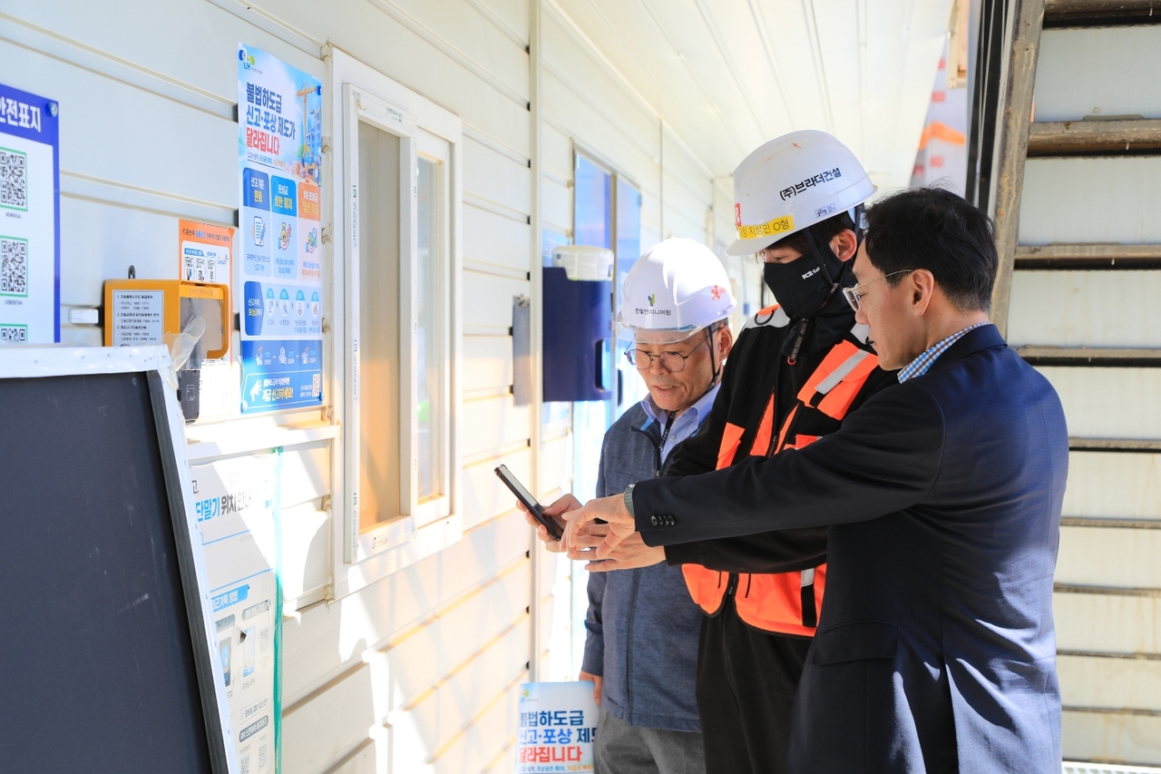 A Korea Land and Housing Corporation official demonstrates how to scan a QR code displayed on a whistleblower reward program poster. [Korea Land and Housing Corporation]