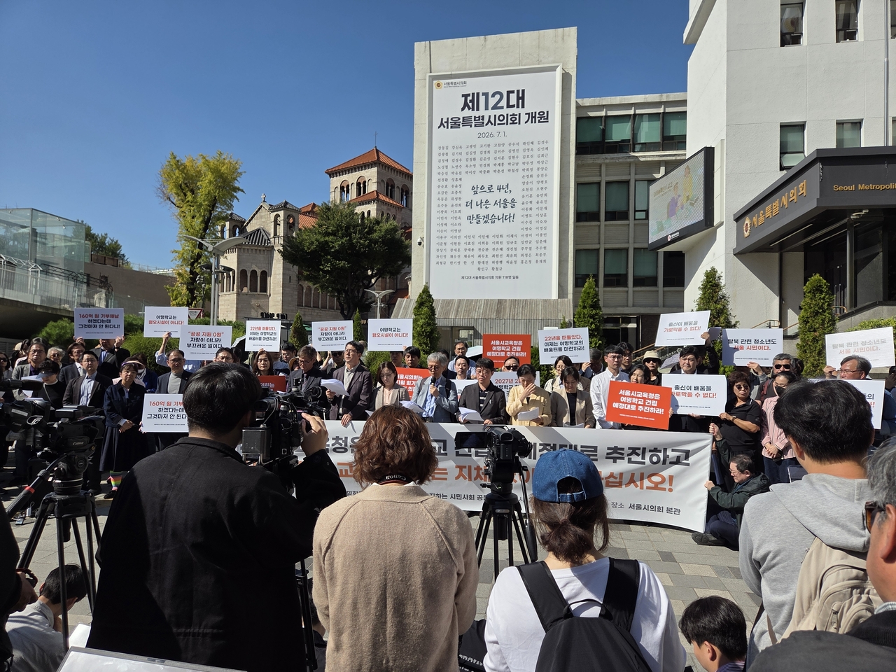 Supporters of Yeomyung School hold signs calling for the construction of a permanent campus during a press conference outside the Seoul Metropolitan Council in Seoul on Wednesday. (Hwang Sun-jun/The Korea Herald)