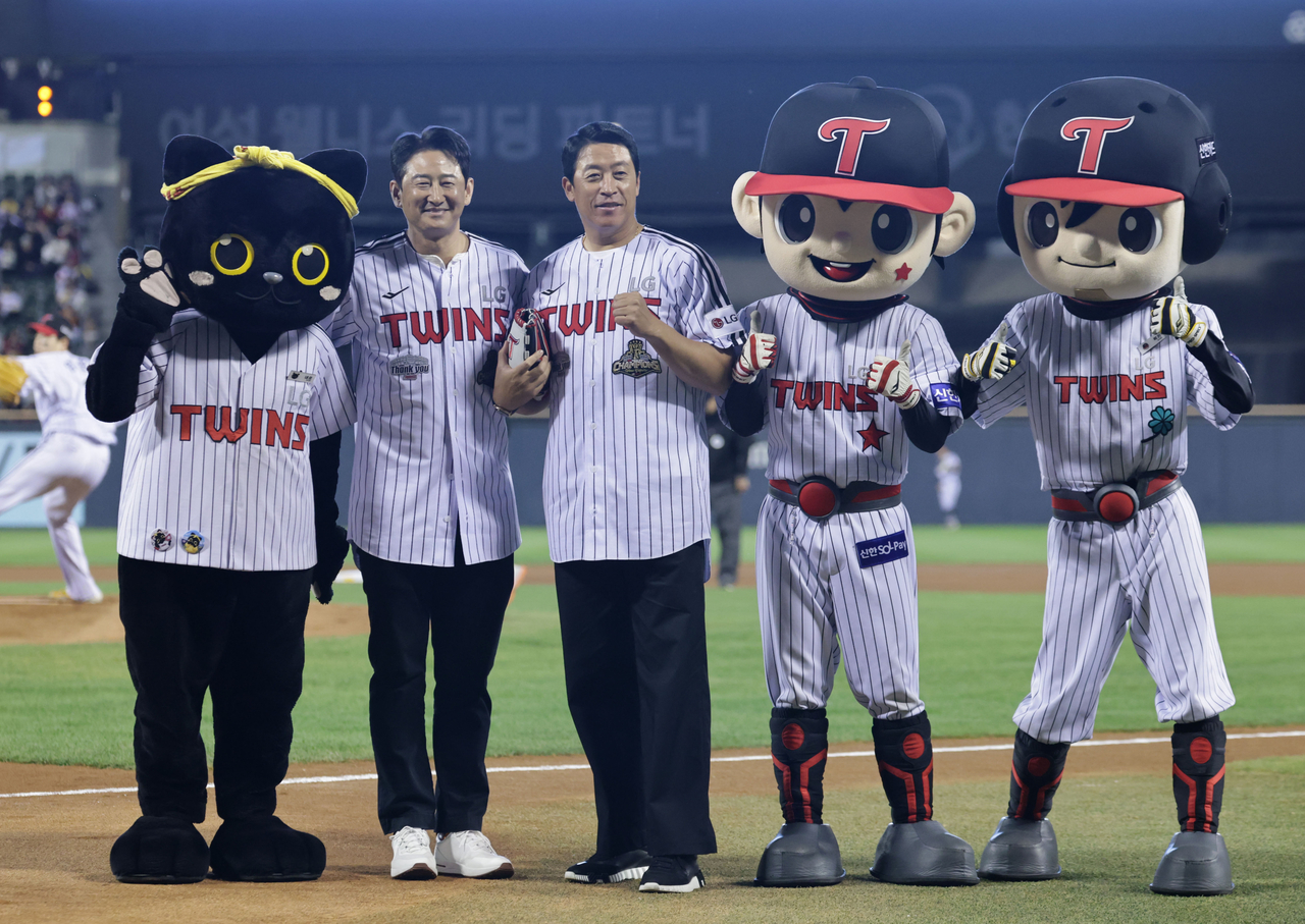 Former LG Twins stars Park Yong-taik (second from left) and Lee Byung-kyu (center) pose for photos with the club's mascots after throwing out the ceremonial first pitches before a Korea Baseball Organization regular-season game against the Doosan Bears at Jamsil Baseball Stadium in Seoul on Wednesday. (Yonhap)