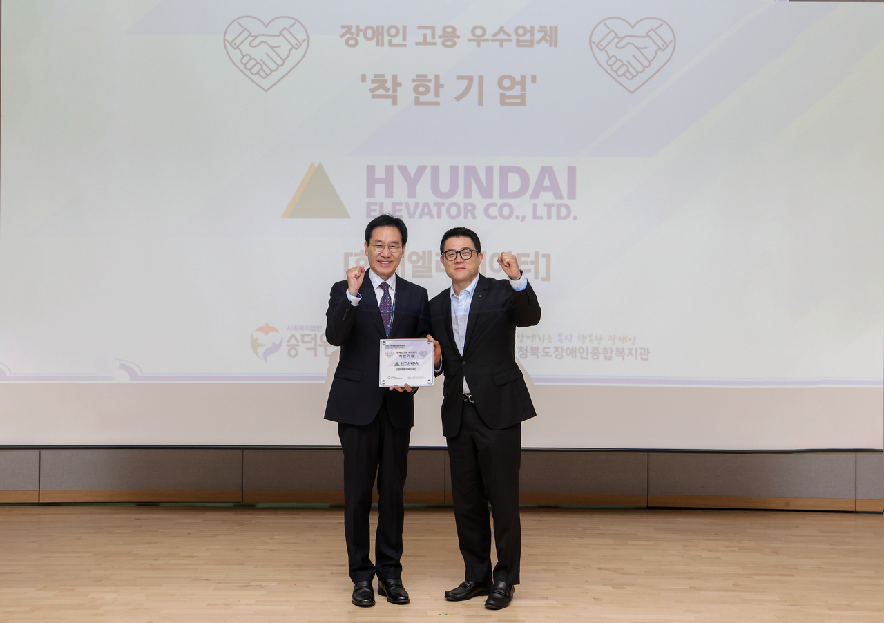 Ahn Ji-hoon, head of human resources at Hyundai Elevator (right), and Lee Jun-ho, a board member of Sungdeokwon social welfare foundation, pose for a photo after a plaque presentation ceremony Wednesday at the UNESCO International Martial Arts Center in Chungju. [Hyundai Elevator]
