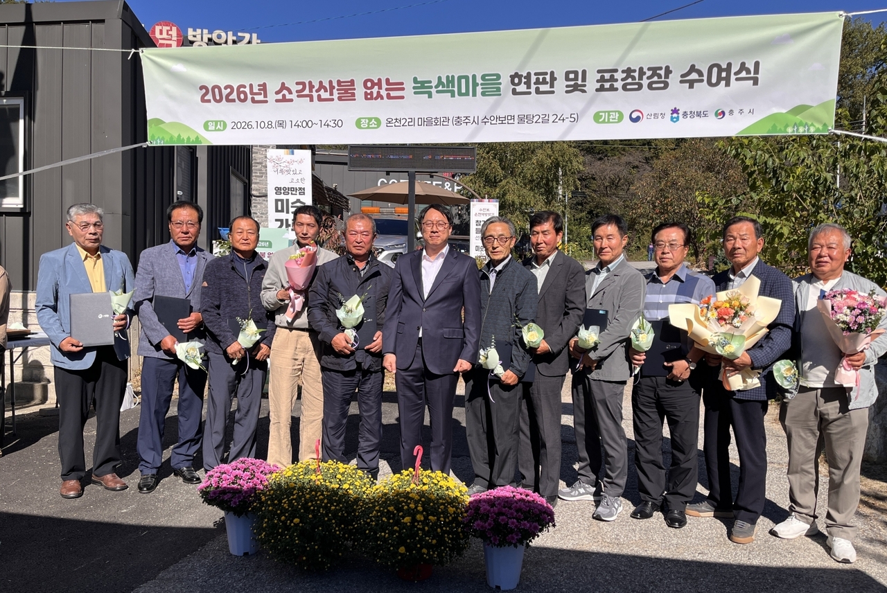Korea Forest Service Deputy Commissioner Im Ha-su (sixth from left) poses for a photo Thursday at the plaque presentation ceremony for outstanding "no open-burning wildfire" green villages, held at the Oncheon 2-ri community center in Suanbo-myeon, Chungju, North Chungcheong Province.