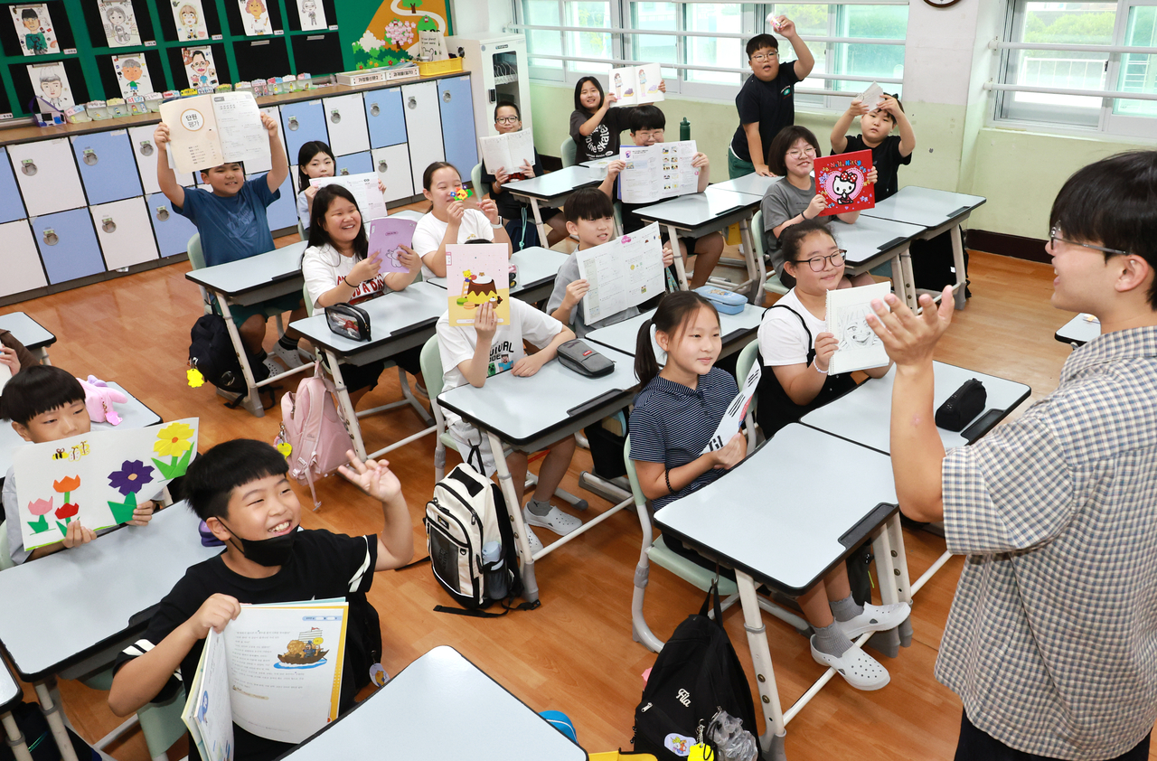 Fourth graders at Daepyeong Elementary School in Busan hold up their art projects on Aug. 18. (Yonhap)
