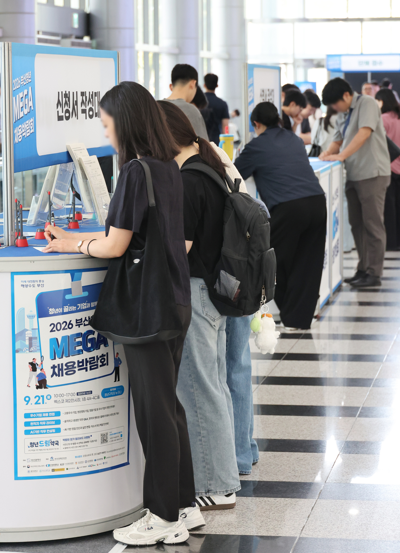 Job seekers fill out application forms at the 2026 Busan Youth Mega Job Fair held at BEXCO's second exhibition hall in Haeundae-gu, Busan, on Sept. 21. A total of 102 leading companies from the Busan area took part, conducting on-site interviews and recruitment consultations for young job seekers. [Yonhap]