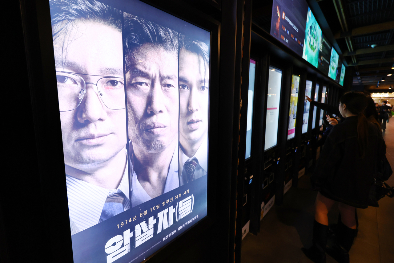 육영수 여사 피격 사건을 다룬 영화 ‘암살자(들)’이 역사 왜곡 논란 속에서 관객 수 200만명을 돌파했다. 4일 영화입장권 통합전산망에 따르면 ‘암살자(들)’은 3일까지 누적 관객수 204만 명을 넘겼다. 이로써 올해 개봉한 작품 중에 9번째로 200만명을 넘긴 작품이 됐다. 사진은 이날 서울의 한 영화관에 걸린 ‘암살자(들)’ 포스터. [연합]