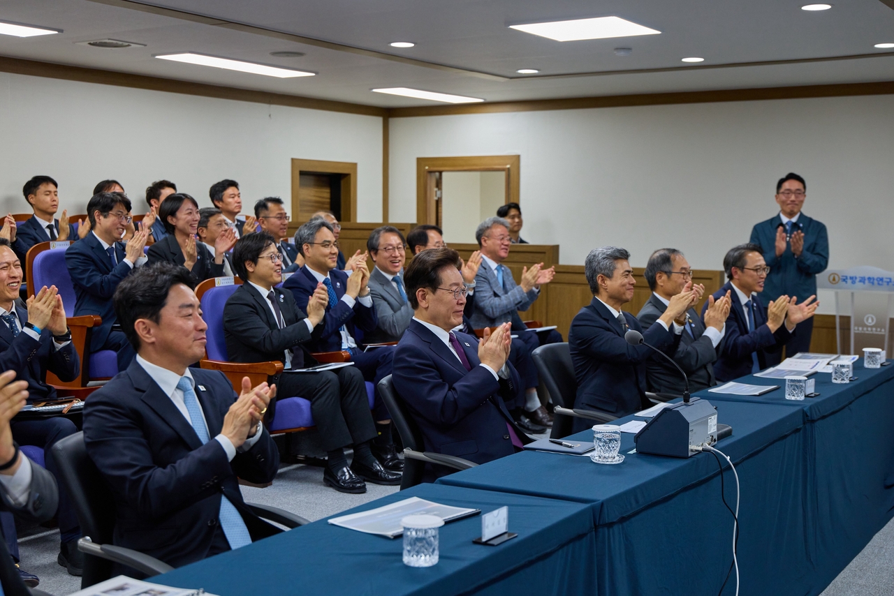 President Lee Jae Myung (second from left) applauds alongside officials from the Agency for Defense Development and other government officials at a situation room Thursday. Defense Minister Kang Shin-chul is seen to Lee's left and presidential chief of staff Kang Hoon-sik to his right. (Lee's X account)