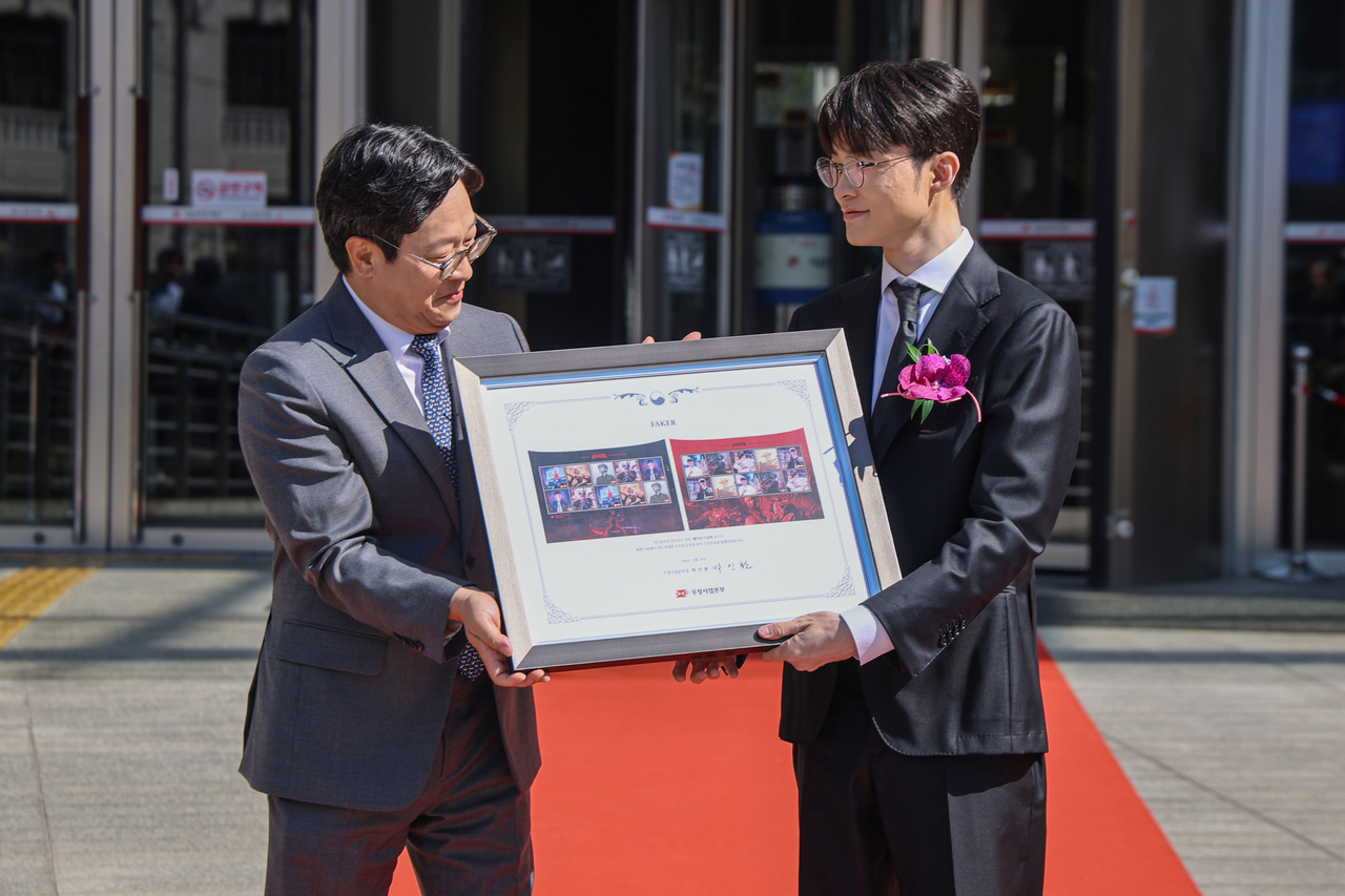 Lee Sang-hyeok, known globally by his gaming moniker Faker, right, receives commemorative stamps from Park In-hwan, head of Korea Post, during a ceremony at the Seoul Central Post Office in central Seoul on Saturday. (Yonhap)