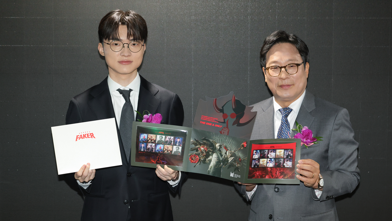 Lee Sang-hyeok, known globally by his gaming moniker Faker, left, poses for a photo with Park In-hwan, head of Korea Post, holding commemorative stamps at the Seoul Central Post Office in central Seoul on Saturday. (Yonhap)