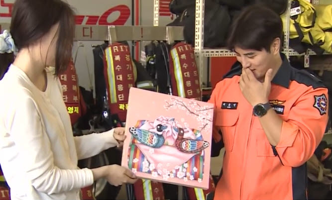 Kim Ye-bin (left) receives a painting of mandarin ducks from firefighter Chae Jong-young in Uijeongbu, Gyeonggi Province, on Sunday. (Yonhap News TV)