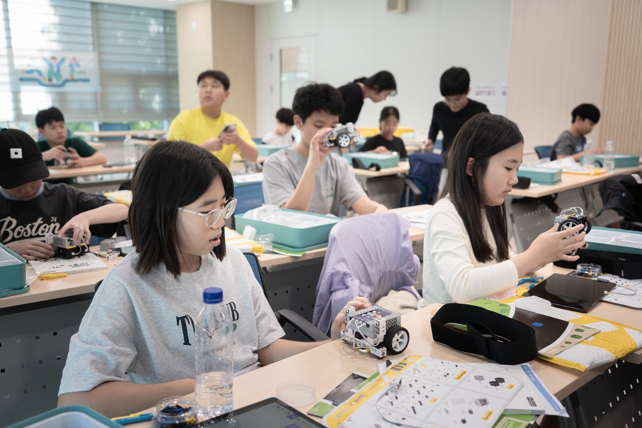 CJ올리브네트웍스가 경기도교육청 ‘신나는공유학교’와 연계해 진행한 초등학생 대상 ‘AX창의캠프’에서 참여 학생들이 자율주행 차량 모형을 조립하고 있다. [CJ올리브네트웍스 제공]