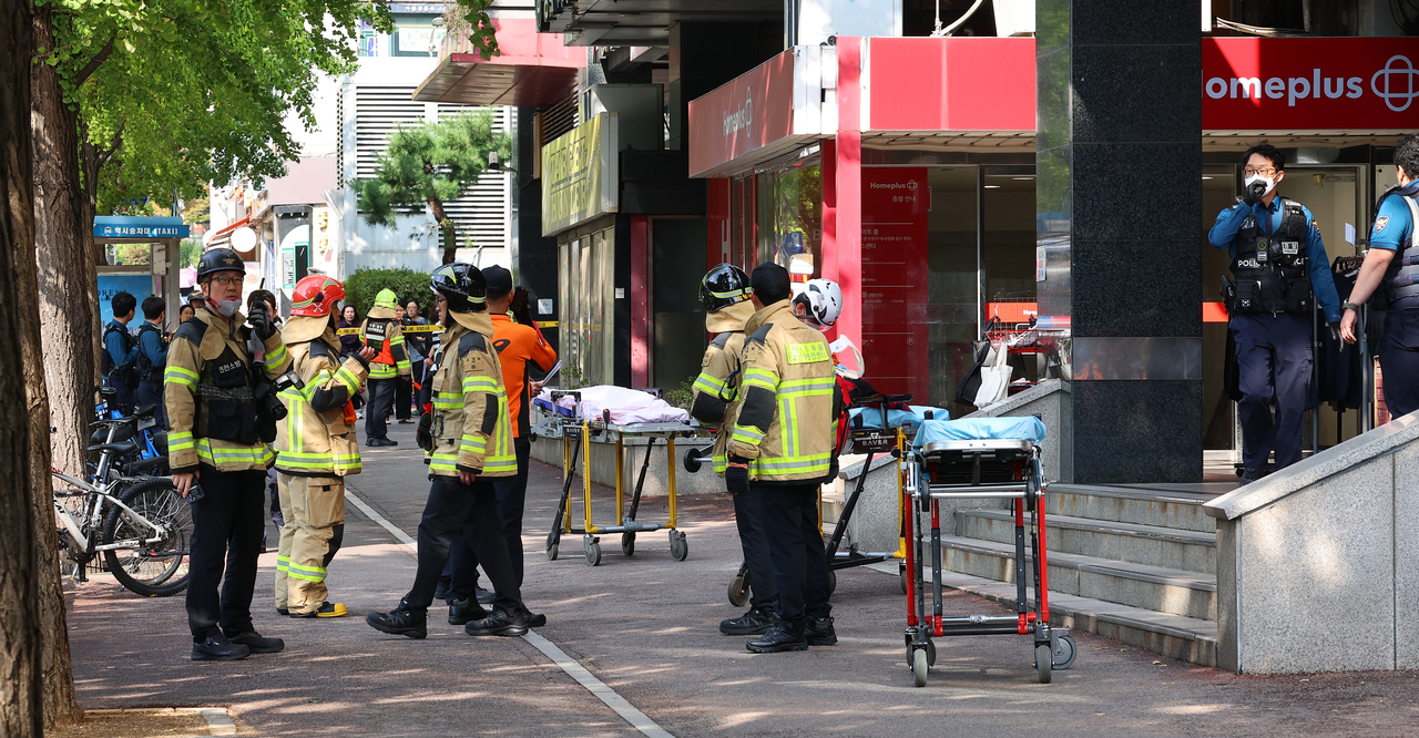 Police officers and firefighters stand by with stretchers in front of a Homeplus branch in Guwol, Incheon, on Oct. 13, following a random stabbing attack. (Yonhap)