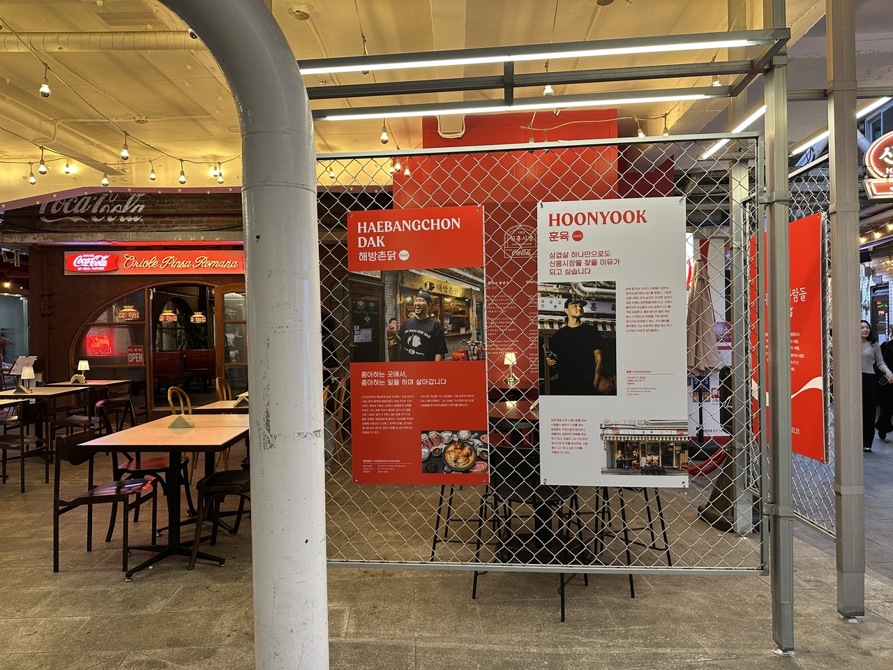 A temporary Coca-Cola exhibition introduces the people behind Sinheung Market’s shops through photographs and videos. The exhibition opened Sept. 1 for a roughly two-month run. (Tammy Park/The Korea Herald)