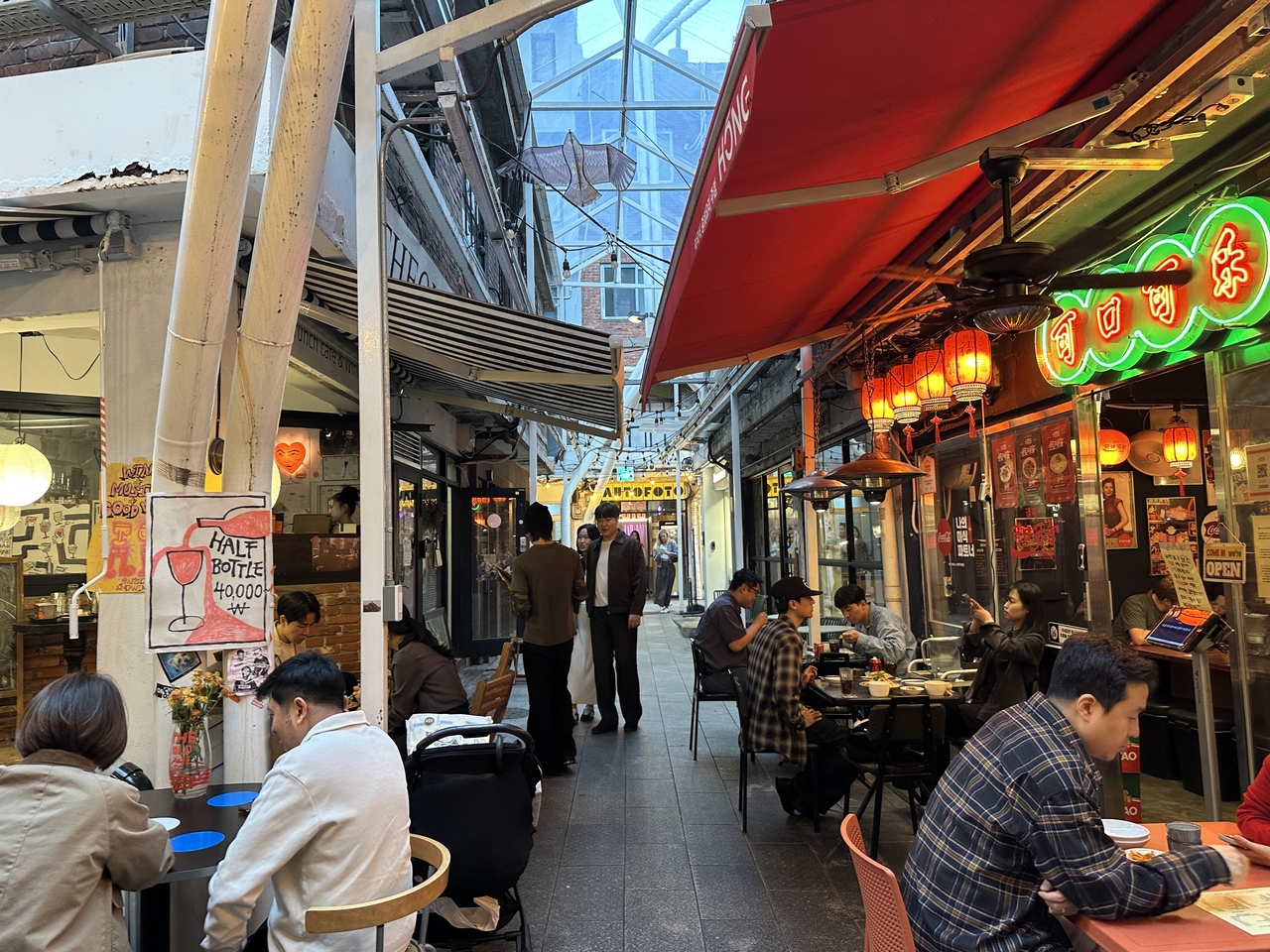 The same alley at Sinheung Market after renovation, with diners seated outside restaurants on Oct. 13. (Tammy Park/The Korea Herald)