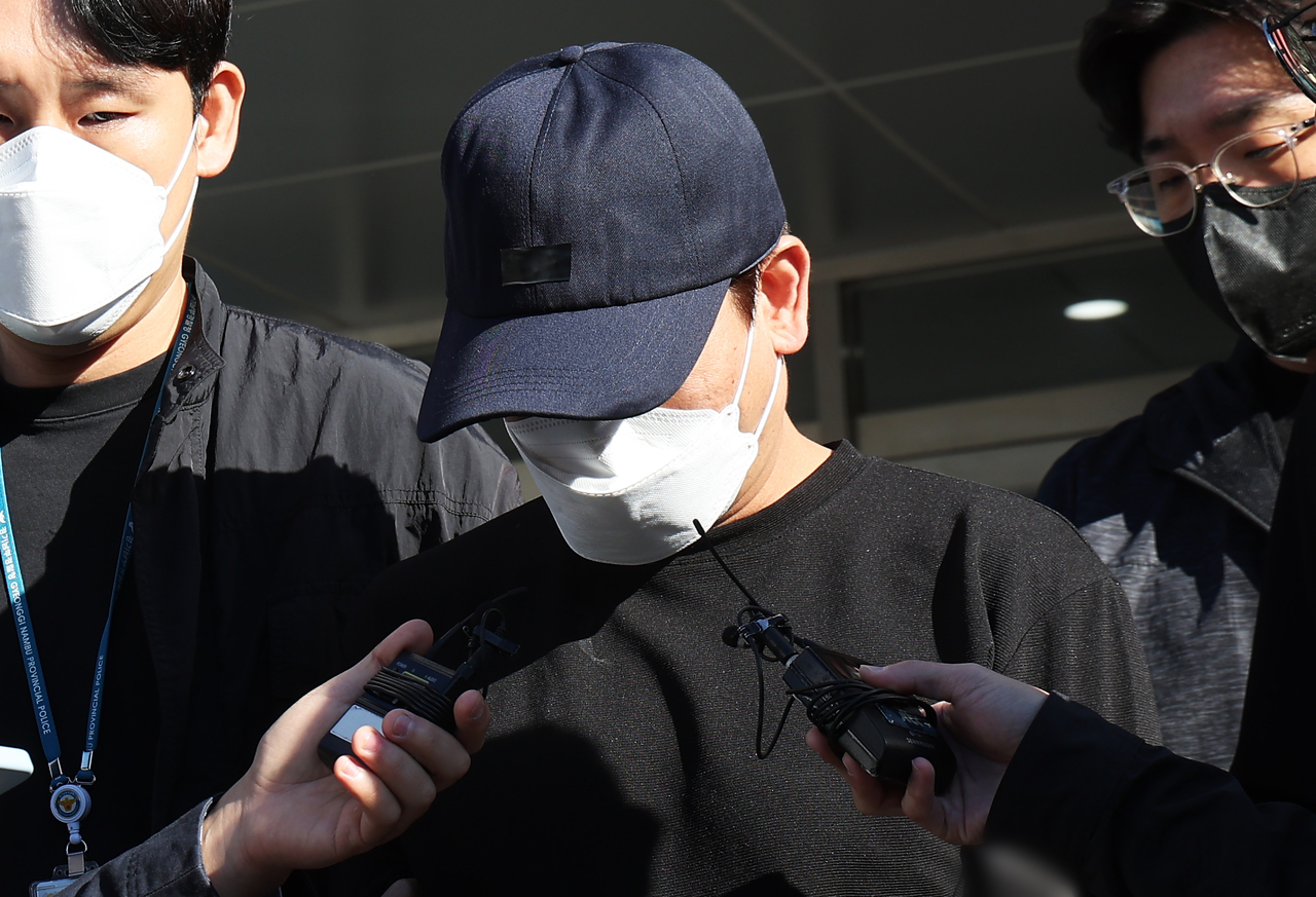 A father is questioned by reporters as he makes his way to a court questioning over allegations of beating his 2-month-old daughter to death in Seoul on Wednesday. (Yonhap)