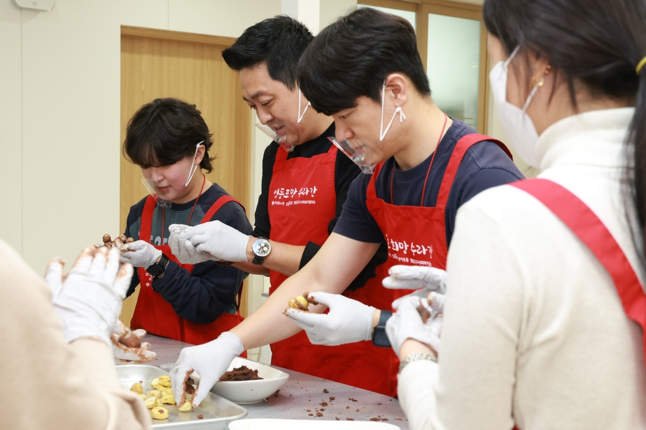 Employees of Lotte Home Shopping make glutinous rice cakes using Gongju chestnuts to be delivered to elderly people living alone in Yeongdeungpo-gu during the inaugural run of the "TEAM Sharing Lunch" program at Huimang Suragan inside the Yeongdeungpo-gu Office annex in Seoul on Wednesday. [Lotte Home Shopping]