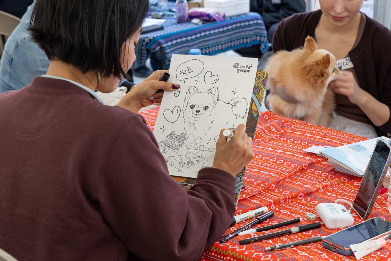 A visitor's pet dog is drawn in caricature at a Mapo-gu event booth