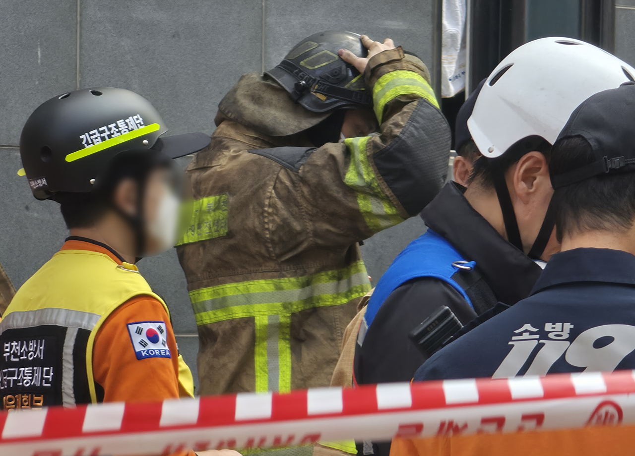 A firefighter in soot-blackened protective gear walks after battling the blaze in Bucheon, Gyeonggi Province, on Friday. (Yonhap)