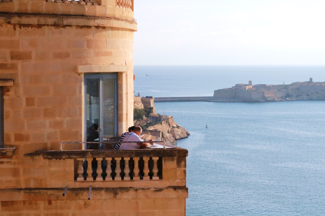 People sit on a balcony of a house in Valletta, Malta, that looks out on the Grand Harbor. (Son Ji-hyoung/The Korea Herald)