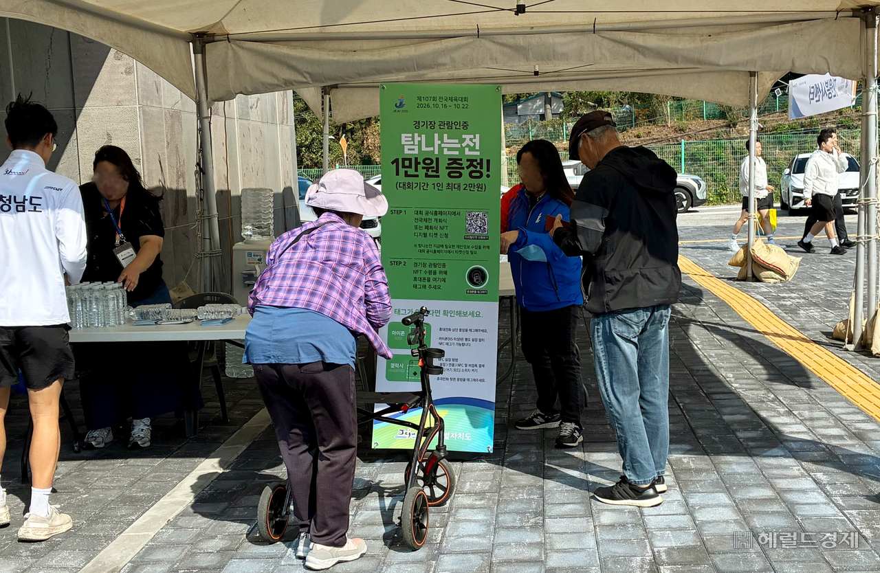 지난 17일 오전 제주 서귀포시 종합체육관에 마련된 전국체육대회 펜싱 경기장 앞에서 관람객들이 대체불가능토큰(NFT) 관람 인증을 위해 휴대전화를 확인하고 있다. 현장에 설치된 NFC 태그에 휴대전화를 갖다 대면 관람 인증 NFT 아트워크를 발급받을 수 있다. 김서현 기자