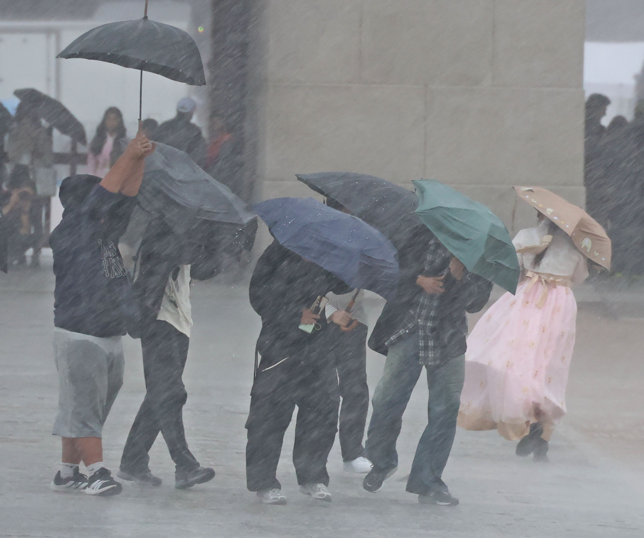 Visitors huddle under umbrellas to shield themselves from the rain at Gyeongbokgung in Jongno-gu, Seoul, Sunday. (Yonhap)