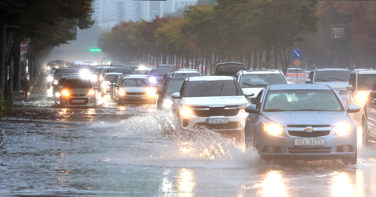 Vehicles drive through a flooded road in Yeonsu-gu, Incheon, Sunday. (Yonhap)
