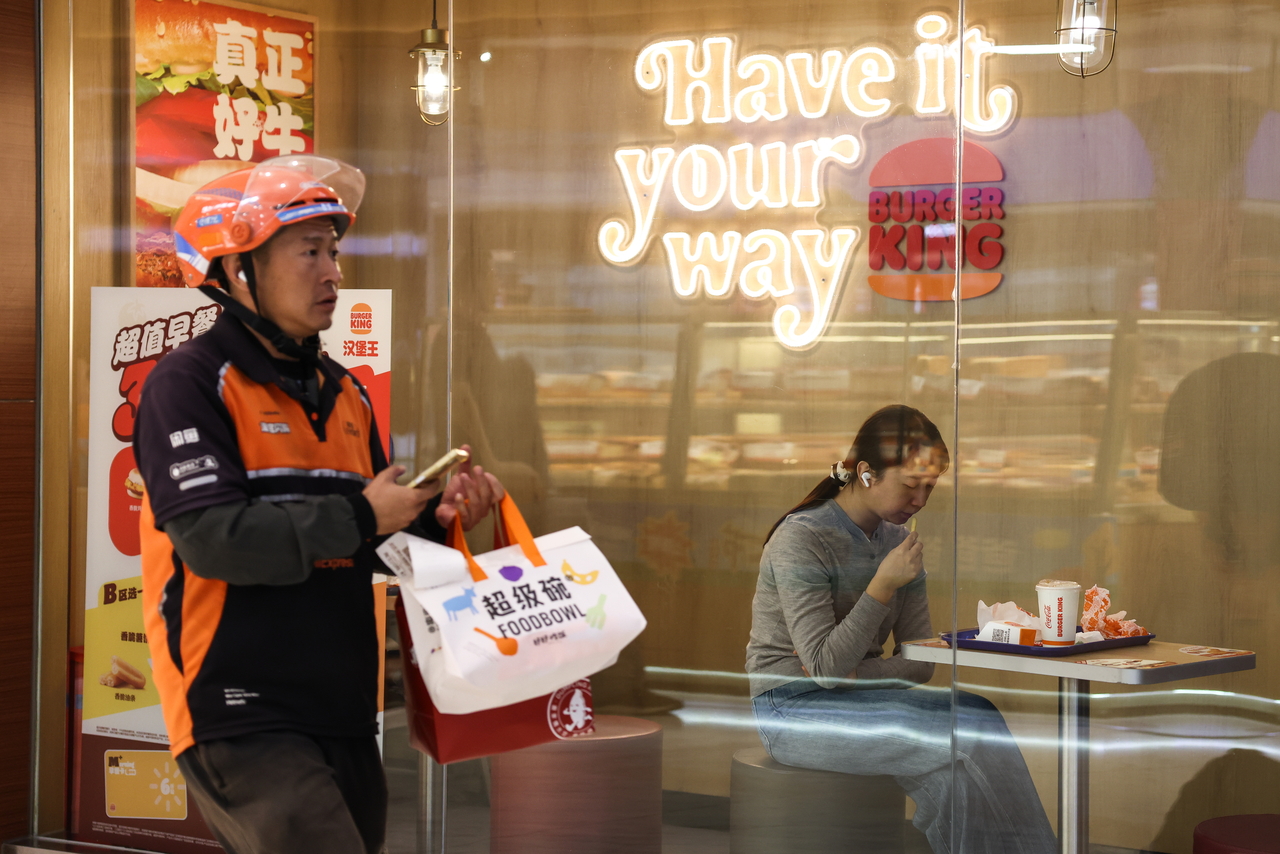 A delivery worker passes a restaurant in Beijing, China. [EPA]