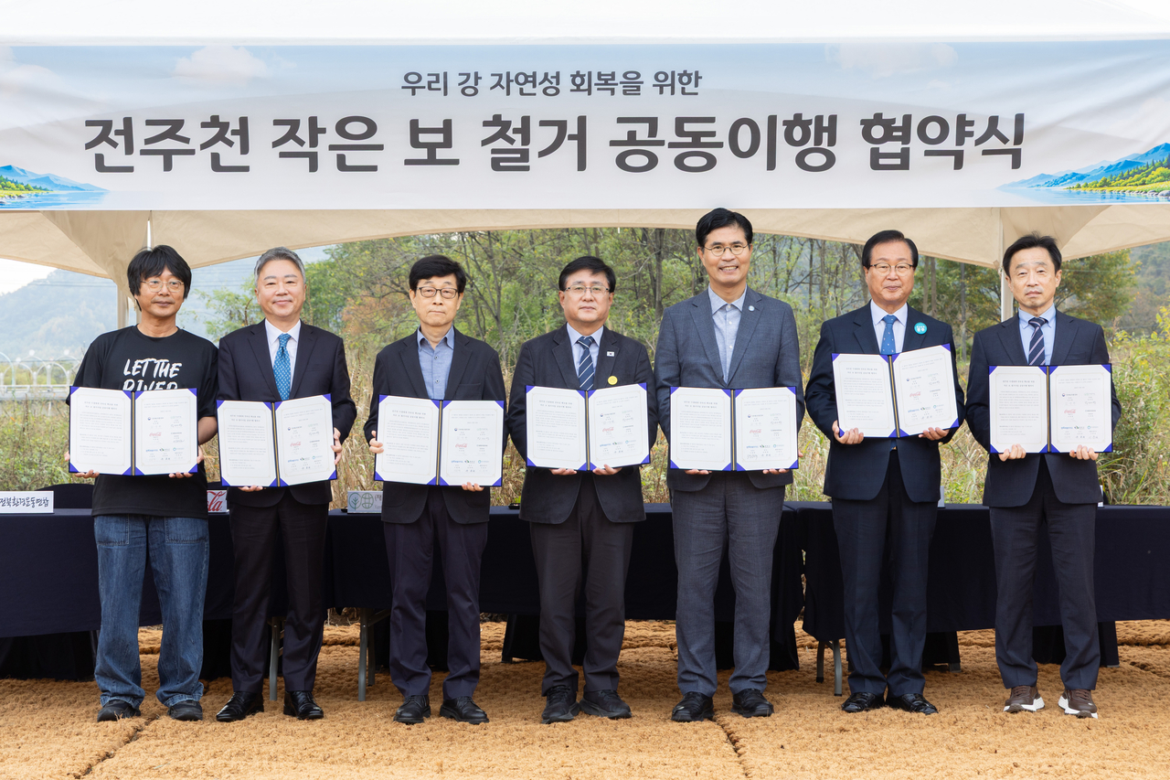 19일 전북 완주군 소재 전주천 상죽음보 일원에서 열린 ‘전주천 작은 보 철거를 위한 공동이행 협약식’에서 참석자들이 협약을 체결하고 기념촬영을 하고 있다. 사진 왼쪽부터 이정현 전북환경운동연합 공동대표, 이준엽 한국 코카-콜라 대표이사, 장재연 (재)숲과나눔 이사장, 김성환 기후에너지환경부 장관, 이원택 전북특별자치도지사, 유희태 완주군수, 이준석 한국환경공단 환경시설이사[기후에너지환경부 제공]