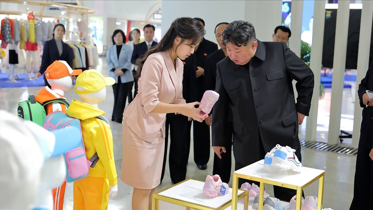 North Korean leader Kim Jong-un examines a pair of pink children's sneakers held up by his daughter, Ju-ae, during a visit to a clothing and footwear exhibition on Monday, in this image aired by Korean Central Television on Tuesday. (Yonhap)