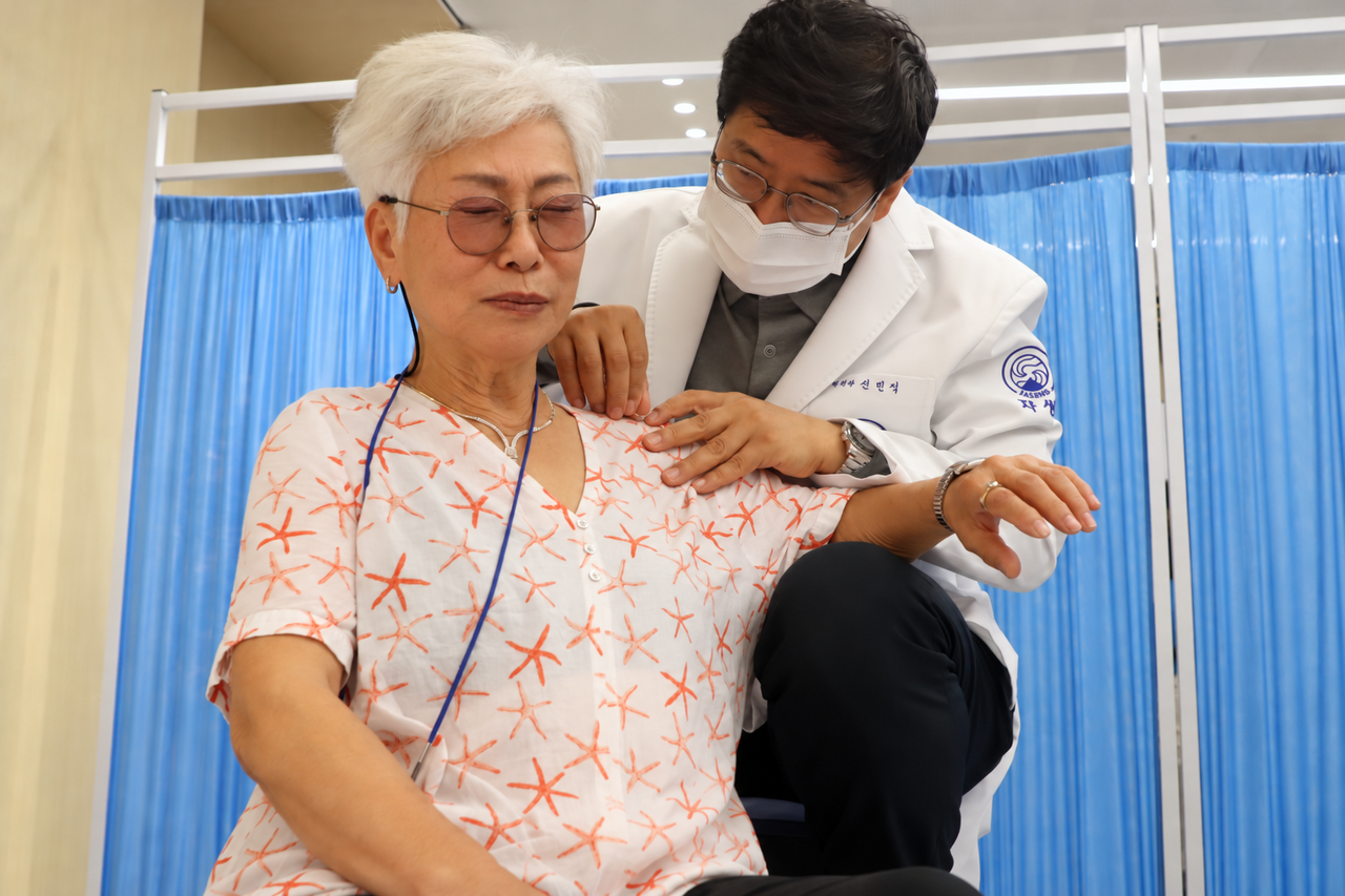 자생의료재단 신민식 사회공헌위원장이 파독 간호사에게 의료봉사를 하고 있다. (출처  자생한방병원)