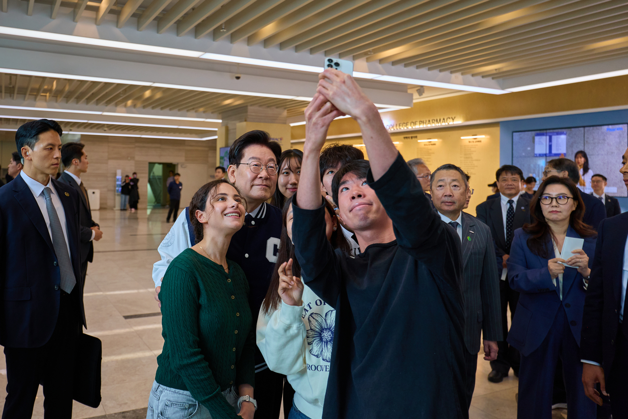 President Lee Jae Myung poses for a photo with students after a ceremony marking the 110th anniversary of Chung-Ang University in  Seoul on Oct. 16. (Cheong Wa Dae via Yonhap)