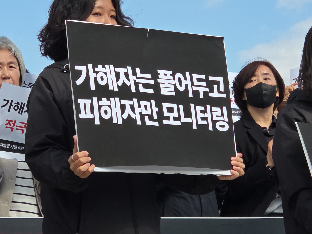 A participant at a Korea Women's Hot Line press conference on the Act on Punishment of Crime of Stalking holds a placard that reads, “Perpetrators are left free. Only victims are monitored,” in Seoul on Wednesday. (Hwang Sun-jun/The Korea Herald)