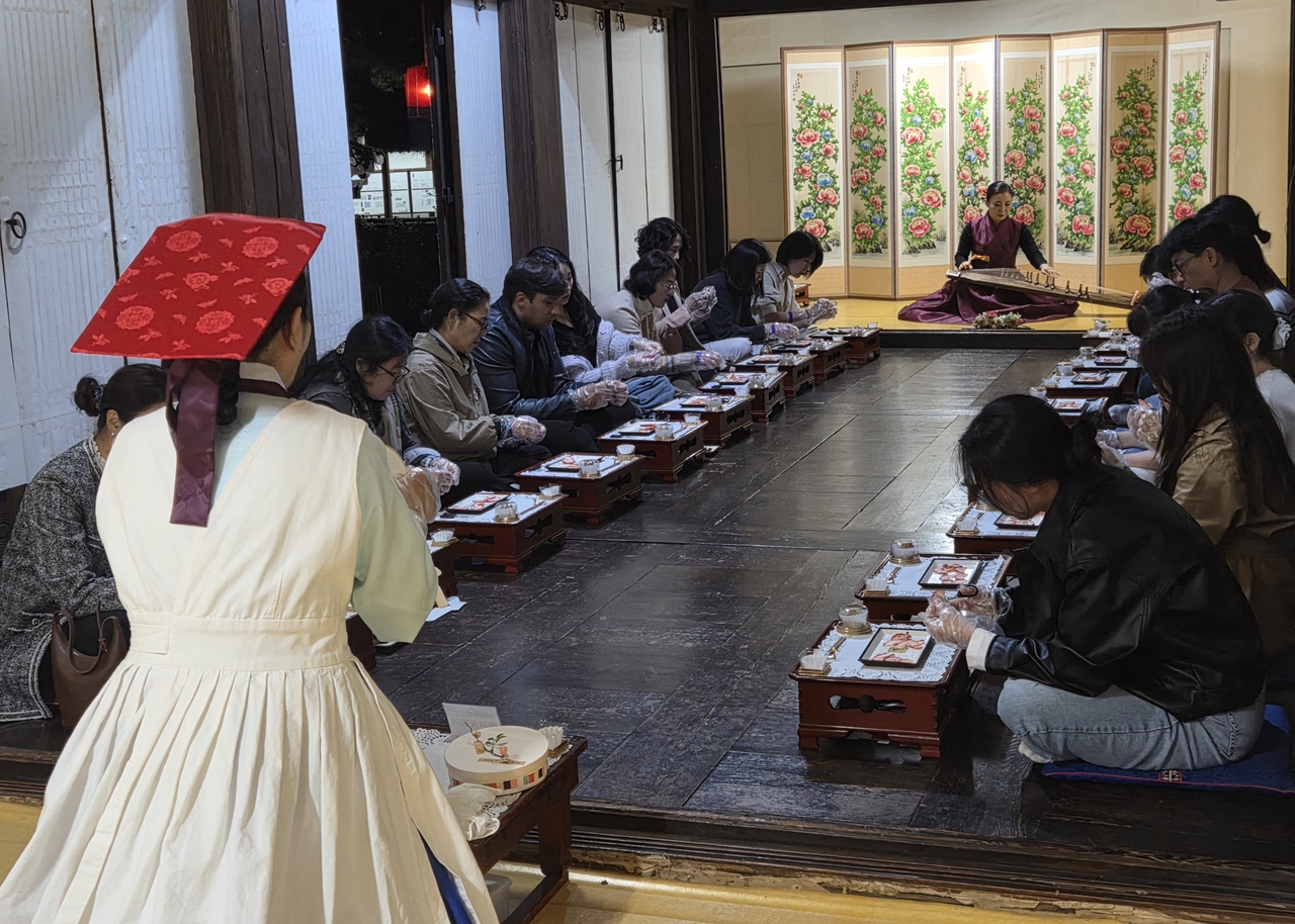 Participants make traditional Korean desserts during a session of Unhyeongung Night Oasis — Moonlight Tea House on Tuesday. (Park Yuna/The Korea Herald)