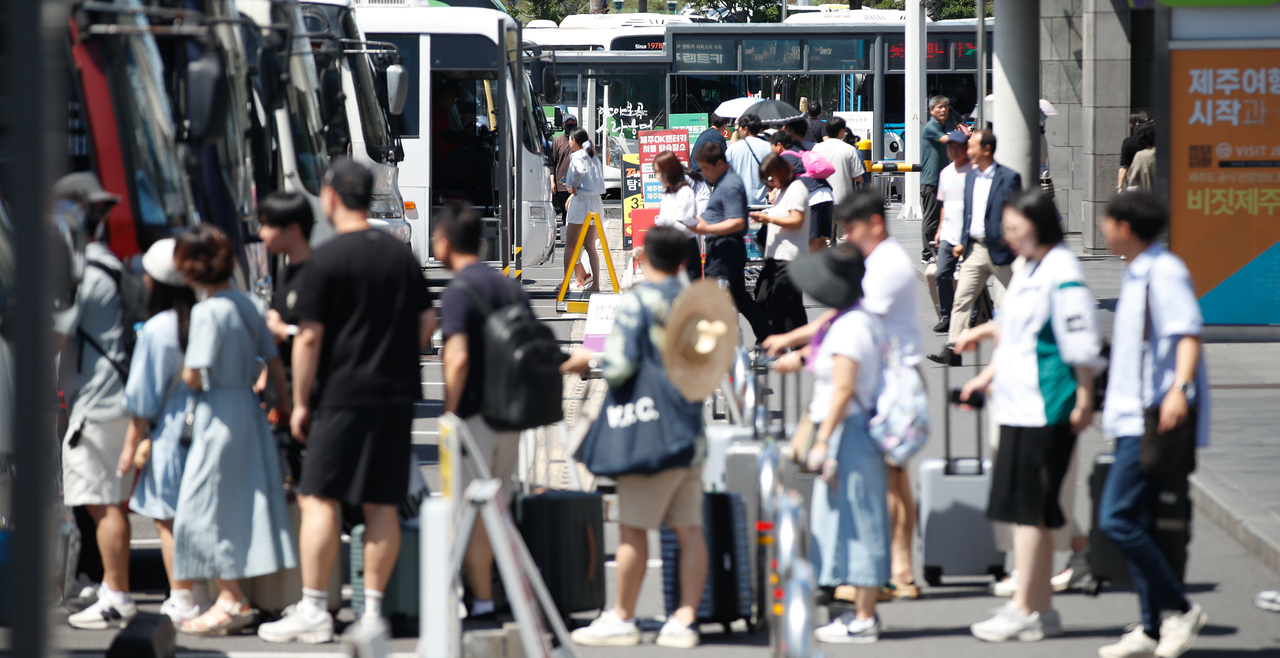 Tourists board a shuttle bus connecting Jeju International Airport to rental car companies at the airport's rental car hub. [Newsis]