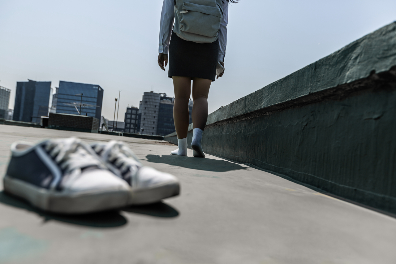 A high school student walks on a school rooftop, leaving their shoes behind. (Getty Images Bank)