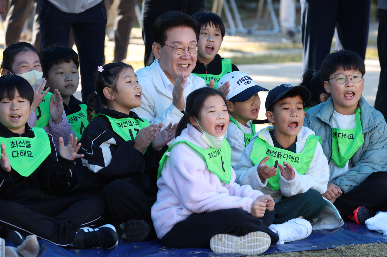 이재명 대통령이 22일 전북 익산 왕궁초등학교에서 열린 가을 체육한마당에서 학생들과 응원을 하고 있다. [연합]