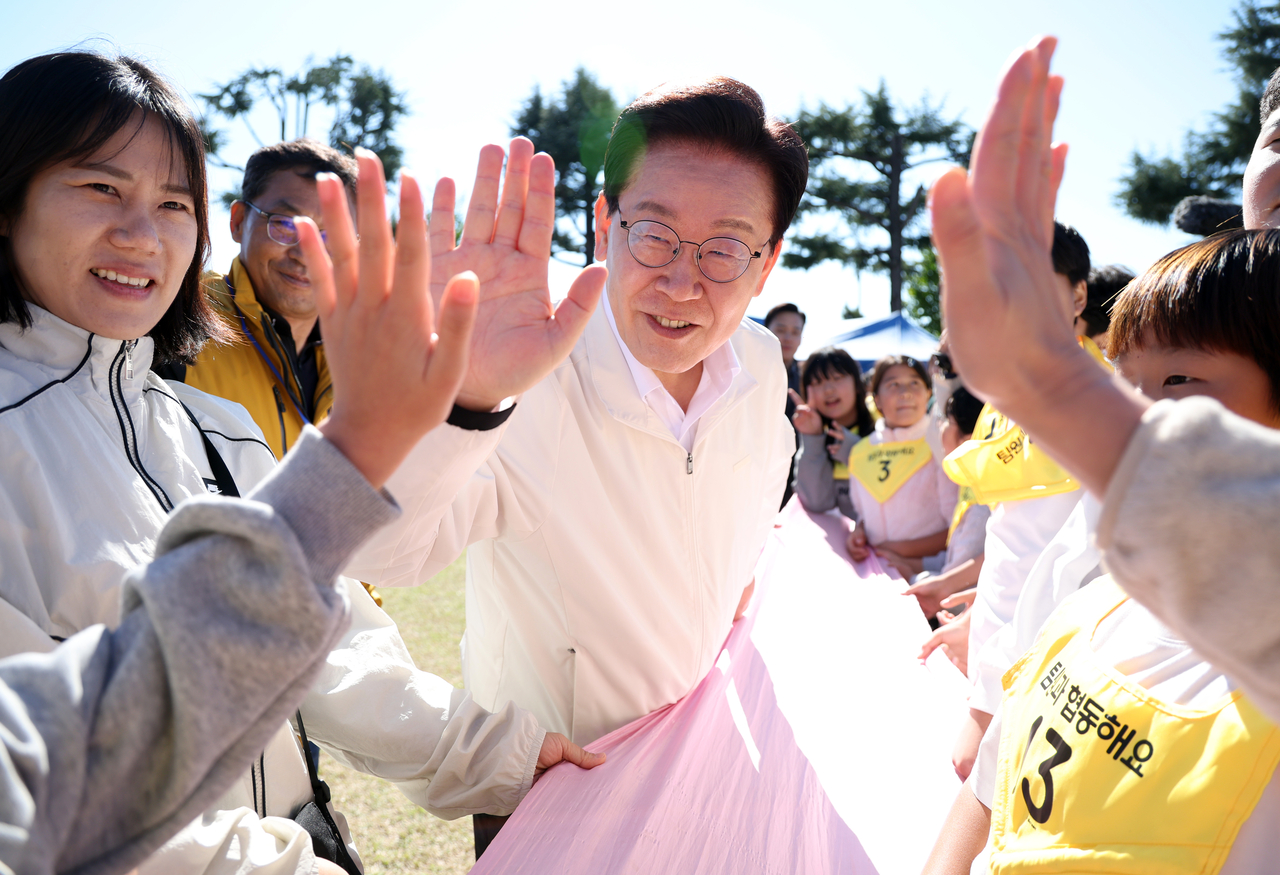 이재명 대통령이 22일 전북 익산 왕궁초등학교에서 열린 가을 체육한마당에서 함께 경기를 한 학생들을 격려하고 있다. [연합]