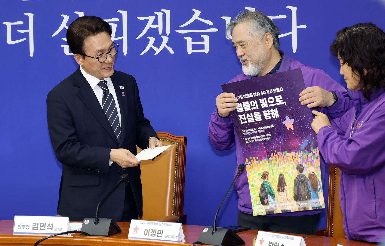 Democratic Party of Korea leader Kim Min-seok receives an invitation to the fourth anniversary memorial service for the Oct. 29 Itaewon crowd crush from Lee Jeong-min, chair of the bereaved families council's steering committee, after meeting with a delegation of the council at the National Assembly on Thursday. (Yonhap)