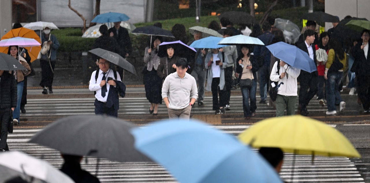 Commuters make their way to work under umbrellas at the Yeouido transit center in Seoul on Wednesday, as autumn rain fell across the country. (Lee Sang-sub)