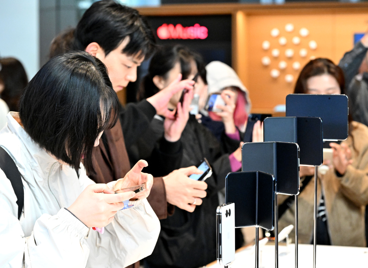 Visitors try out Apple's new iPhone Duo at Apple Myeongdong in central Seoul on Friday, the device's first day of sales in South Korea. (Im Se-jun/The Korea Herald)