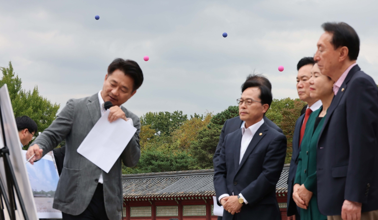 김석기 의원(오른쪽)을 비롯한 국회 문화체육관광위원회 국민의힘 의원들이 15일 서울 종로구 종묘에서 정전 월대 현장 시찰을 하고 있다. 의원들 뒤로 세운4구역 건축물 높이를 표시한 애드벌룬이 설치돼 있다.  [연합뉴스 제공]